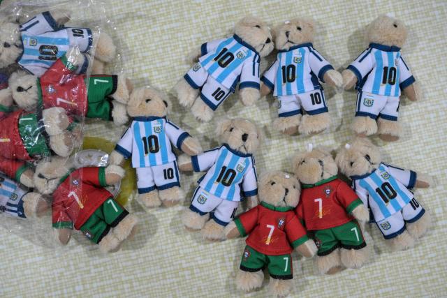 This photo taken on June 5, 2026 shows merchandise of Lionel Messi of Argentina and Cristiano Ronaldo of Portugal -- football teams that will participate in the FIFA World Cup 2026 -- at the All Star Partner factory in Yiwu in eastern China's Zhejiang province. Stuffed "goat" plushies donning Lionel Messi's famous Argentina no. 10 pepper a factory tabletop in eastern China, where sellers are betting on the country's lucrative fan market for a World Cup boost. (Photo by Hector RETAMAL / AFP) / To go with 'CHINA-CONSUMPTION-FBL,FOCUS' by Mary YANG
