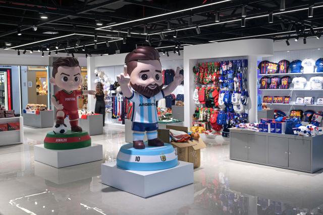 This photo taken on June 5, 2026 shows merchandise of football teams that will participate in the FIFA World Cup 2026 at a shop in Yiwu in eastern China's Zhejiang province. Stuffed "goat" plushies donning Lionel Messi's famous Argentina no. 10 pepper a factory tabletop in eastern China, where sellers are betting on the country's lucrative fan market for a World Cup boost. (Photo by Hector RETAMAL / AFP) / To go with 'CHINA-CONSUMPTION-FBL,FOCUS' by Mary YANG