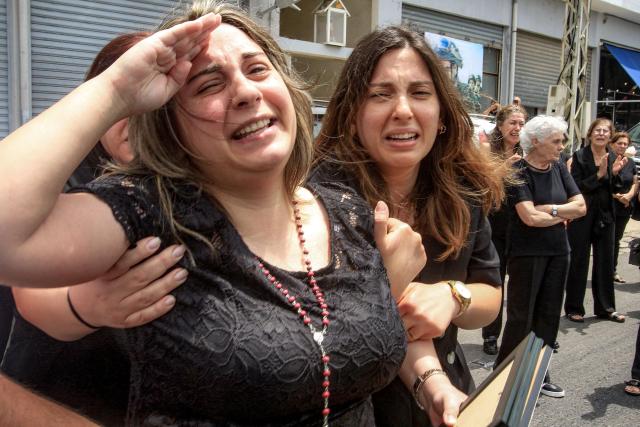TOPSHOT - Rosette Tannous, wife of Lebanese army captain Elie Khoury who was killed by Israeli bombardment, salutes as mourners carry her husband's coffin past during the funeral in his home village of Kfar Jarra near Jezzine in southern Lebanon on June 8, 2026. An Israeli strike in southern Lebanon killed three soldiers, Beirut's military said on June 6, as its chief travelled to Pakistan to meet with a key mediator in efforts to end the Middle East war. Israel has launched an operation in Lebanon to root out the Tehran-backed armed group Hezbollah, which drew Lebanon into the wider Middle East war by launching missiles on behalf of its sponsor. (Photo by Mahmoud ZAYYAT / AFP) / 