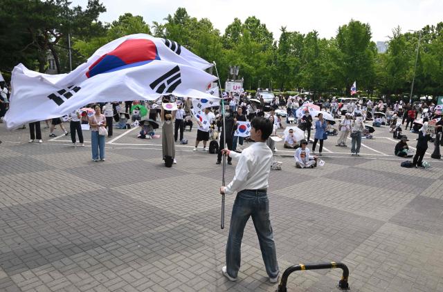 South Korean protesters wave the national flags outside a vote-counting centre in Seoul on June 10, 2026, to call for a rerun of the local elections due to a shortage of ballot papers. South Korean authorities agreed on June 9 to launch an investigation into ballot paper shortages at recent local elections, local media reported, following widespread protests. (Photo by Jung Yeon-je / AFP)