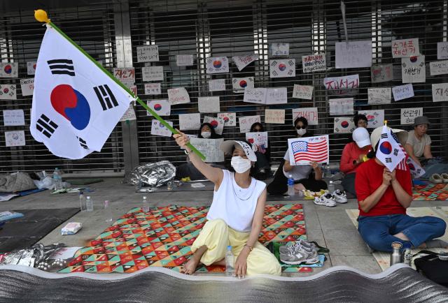 South Korean protesters wave the national flags outside a vote-counting centre in Seoul on June 10, 2026, to call for a rerun of the local elections due to a shortage of ballot papers. South Korean authorities agreed on June 9 to launch an investigation into ballot paper shortages at recent local elections, local media reported, following widespread protests. (Photo by Jung Yeon-je / AFP)