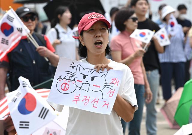 South Korean protesters wave the national flags outside a vote-counting centre in Seoul on June 10, 2026, to call for a rerun of the local elections due to a shortage of ballot papers. South Korean authorities agreed on June 9 to launch an investigation into ballot paper shortages at recent local elections, local media reported, following widespread protests. (Photo by Jung Yeon-je / AFP)