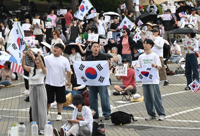 South Korean protesters wave the national flags outside a vote-counting centre in Seoul on June 10, 2026, to call for a rerun of the local elections due to a shortage of ballot papers. South Korean authorities agreed on June 9 to launch an investigation into ballot paper shortages at recent local elections, local media reported, following widespread protests. (Photo by Jung Yeon-je / AFP)