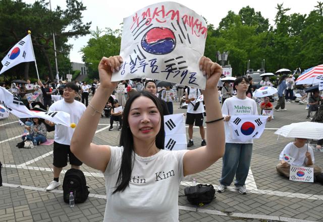 South Korean protesters wave the national flags outside a vote-counting centre in Seoul on June 10, 2026, to call for a rerun of the local elections due to a shortage of ballot papers. South Korean authorities agreed on June 9 to launch an investigation into ballot paper shortages at recent local elections, local media reported, following widespread protests. (Photo by Jung Yeon-je / AFP)