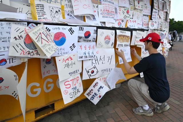 A South Korean protester attaches a message calling for a rerun of the local elections due to a shortage of ballot papers outside a vote-counting centre in Seoul on June 10, 2026. South Korean authorities agreed on June 9 to launch an investigation into ballot paper shortages at recent local elections, local media reported, following widespread protests. (Photo by Jung Yeon-je / AFP)