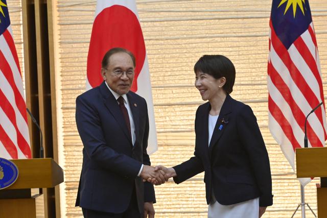 Japan's Prime Minister Sanae Takaichi (R) and Prime Minister Anwar Ibrahim (L) shake hands at the end a joint press announcement following their bilateral meeting at the Prime Minister’s Office in Tokyo on June 10, 2026. (Photo by David Mareuil / POOL / AFP)