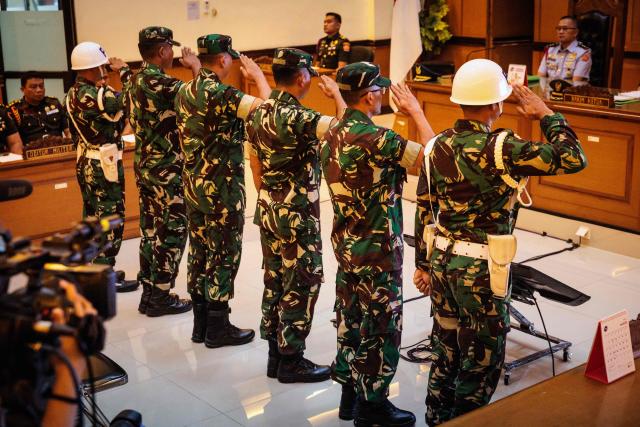 Four Indonesian military personnel accused of throwing acid at a human rights activist salute as they attend a verdict hearing at a military court in Jakarta on June 10, 2026. A military court in Indonesia on June 10 sentenced four soldiers to up to three years in prison for an acid attack on an activist critical of perceived militarisation of the government. (Photo by Yasuyoshi Chiba / AFP)