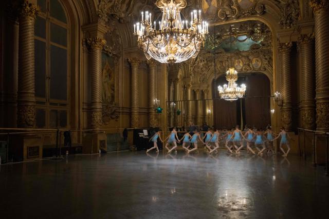 Female students from the 6th division of the Paris Opera Dance School warm up before a performance in the Foyer de la Danse at the Opera Garnier in Paris on December 15, 2024. It is a tradition passed down orally, from one generation of young dancers to the next: at the Paris Opera Ballet School, students are taught the art of French classical ballet, a three-century-old artistic heritage that is attracting more and more foreign dancers. (Photo by JOEL SAGET / AFP)