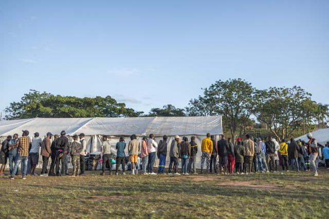 Displaced foreign nationals stand in a queue to give their personal information to volunteers at a park in Durban on June 10, 2026 after fleeing their homes amid fears of xenophobic attacks. Hundreds of foreign nationals await repatriation to Malawi from South Africa following xenophobic violence in the country. Foreign nationals have told of intimidation and beatings by mobs going door-to-door to tell them to leave by June 30, a "deadline" regularly broadcast across social media, even though it has no official backing. Ghana, Mozambique and Malawi are among countries that have repatriated hundreds of their nationals this month, most of whom South Africa says did not have the correct documentation to be in the country. (Photo by RAJESH JANTILAL / AFP)