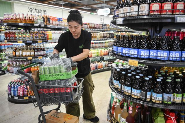 A worker arranges products on a shelf in a store in Beijing on June 10, 2026. Chinese consumer prices remained stable in May, as official data on June 10, 2026 showed the impact of soaring energy prices had started to fade, while increased demand for AI-linked tech goods pushed factory gate costs up for a third straight month. (Photo by Pedro PARDO / AFP)
