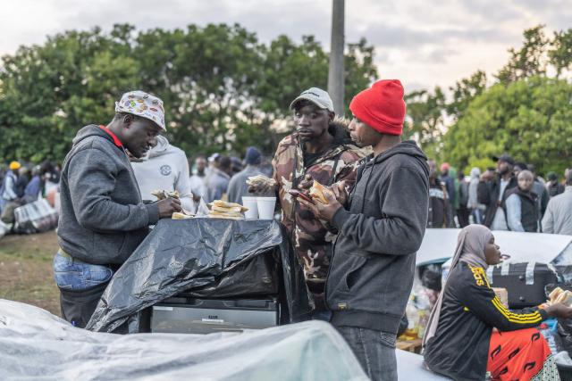 Foreign nationals have a meal at a park in Durban on June 10, 2026 while taking refuge with others after fleeing their homes amid fears of xenophobic attacks. Hundreds of foreign nationals await repatriation to Malawi from South Africa following xenophobic violence in the country. Foreign nationals have told of intimidation and beatings by mobs going door-to-door to tell them to leave by June 30, a "deadline" regularly broadcast across social media, even though it has no official backing. Ghana, Mozambique and Malawi are among countries that have repatriated hundreds of their nationals this month, most of whom South Africa says did not have the correct documentation to be in the country. (Photo by RAJESH JANTILAL / AFP)