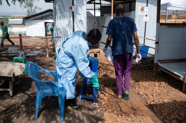 A healthcare worker stands at the entrance of the isolation area at the Rwampara health centre, where confirmed Ebola virus disease patients are being treated in Rwampara on June 9, 2026. He disinfects people and equipment at every entry and exit point to reduce the risk of contamination, including after authorised family visits to isolated relatives. (Photo by Jospin Mwisha / AFP)