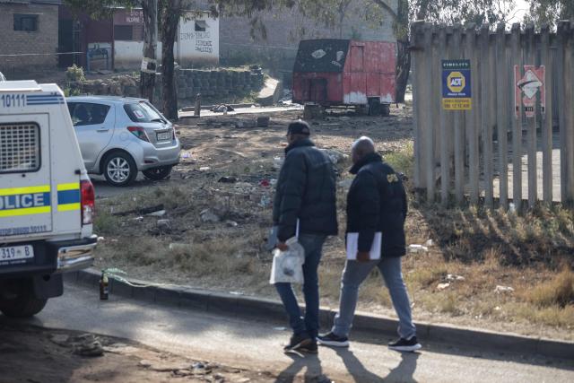 EDITORS NOTE: Graphic content / Crime scene investigators walk near a body of a victim laying in the road at Jumpers informal settlement in Cleveland, east of Johannesburg, on June 10, 2026. Gunmen stormed an informal settlement near Johannesburg and shot dead 12 people overnight, South African police said on June 10, 2026, in the latest mass shooting in the crime-weary country.
The shootings happened before midnight on June 9, 2026 in an impoverished area of metal shacks near where illegal miners were living, police said.
Around 10 attackers were driven to the Jumpers settlement and dropped off before storming the area, a police spokeswoman said. (Photo by EMMANUEL CROSET / AFP)