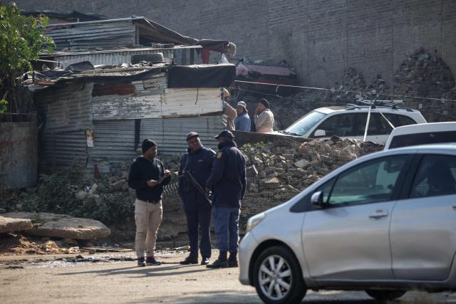 Residents react as South African Police Service (SAPS) officers stand at a crime scene at Jumpers informal settlement in Cleveland, east of Johannesburg, on June 10, 2026. Gunmen stormed an informal settlement near Johannesburg and shot dead 12 people overnight, South African police said on June 10, 2026, in the latest mass shooting in the crime-weary country.
The shootings happened before midnight on June 9, 2026 in an impoverished area of metal shacks near where illegal miners were living, police said.
Around 10 attackers were driven to the Jumpers settlement and dropped off before storming the area, a police spokeswoman said. (Photo by EMMANUEL CROSET / AFP)