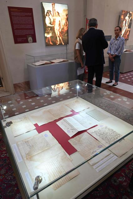 People stand in a room filled with display cases containing manuscripts case containing manuscripts during the exhibition "Atto Melani (16261714). The Secret Voice of Power," as part of a press review, at the Labronica Library of Villa Fabbricotti in Livorno on June 5, 2026. A celebrated singer in the courts of Tuscany, Venice, Rome, and France, a protégé of Cardinal Mazarin and close associate of the Sun King, Louis XIV of France, Atto Melani transformed his theatrical success into an extraordinary diplomatic career. Castrated as a child, he constantly struggled between public prestige and the human burden of his condition, yet he managed to become a political mediator, informer, and protagonist in the conclaves that marked the history of the papacy between 1667 and 1700. (Photo by Andreas SOLARO / AFP)