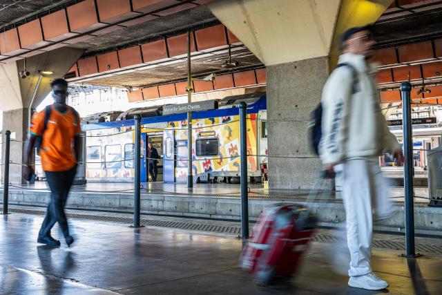 An employee looks on from a train at a platform as travellers walk with luggage at the Saint-Charles train station in Marseille, southern France, on June 10, 2026. Some TGV high-speed trains are cancelled on June 10, morning, as well as regional and suburban trains, as part of a 24-hour strike organized by SNCF unions as the four representative rail unions — CGT-Cheminots, UNSA-Ferroviaire, SUD-Rail and CFDT-Cheminots — called a one-day walkout for their first joint national action since late 2024, to denounce internal restructuring and demand higher wages. (Photo by MIGUEL MEDINA / AFP)