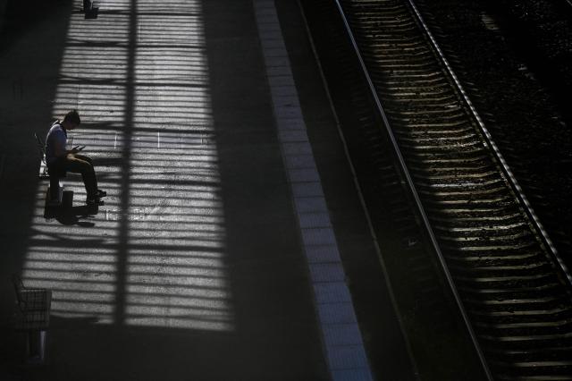 A passenger sits waiting looking at a smartphone on a train platform at a railway station in Beziers, southern France, on June 10, 2026. Some TGV high-speed trains are cancelled on June 10, morning, as well as regional and suburban trains, as part of a 24-hour strike organized by SNCF unions as the four representative rail unions — CGT-Cheminots, UNSA-Ferroviaire, SUD-Rail and CFDT-Cheminots — called a one-day walkout for their first joint national action since late 2024, to denounce internal restructuring and demand higher wages. (Photo by Gabriel BOUYS / AFP)