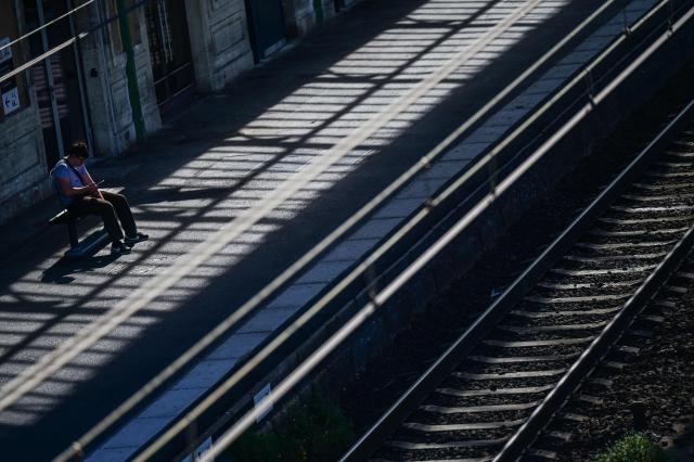 A passenger sits waiting looking at a smartphone on a train platform at a railway station in Beziers, southern France, on June 10, 2026. Some TGV high-speed trains are cancelled on June 10, morning, as well as regional and suburban trains, as part of a 24-hour strike organized by SNCF unions as the four representative rail unions — CGT-Cheminots, UNSA-Ferroviaire, SUD-Rail and CFDT-Cheminots — called a one-day walkout for their first joint national action since late 2024, to denounce internal restructuring and demand higher wages. (Photo by Gabriel BOUYS / AFP)