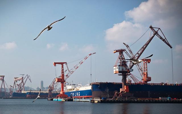 Seagulls fly near the production and operation area of the Dalian Shipbuilding Industrial Group on the coast of Suoyu Bay in Ganjingzi District of Dalian, in northeastern China's Liaoning province on June 10, 2026. (Photo by CN-STR / AFP) / China OUT