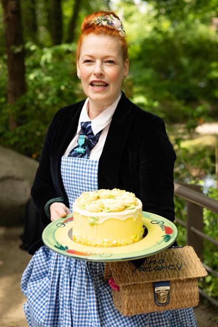 German Tv host Enie van de Meiklokjes poses with a cake to celebrate the name reveal of one month old pygmy hippopotamus Broetchen (Bun) at the Zoologischer Garten zoo in Berlin on June 10, 2026. Born on May 9, 2026 'Broetchen' is the last addition to the pygmy hippopotamus family at the Zoo in the German capital. (Photo by Odd ANDERSEN / AFP)