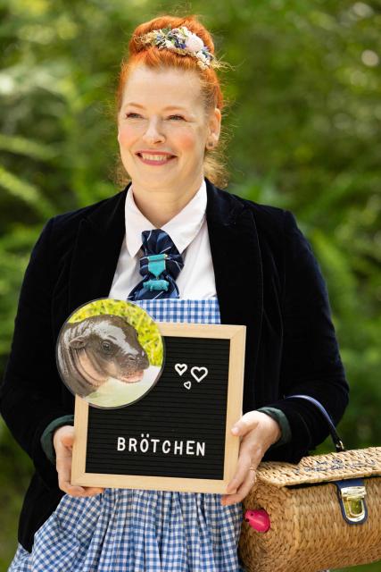 German Tv host Enie van de Meiklokjes poses with a picture of one month old pygmy hippopotamus Broetchen (Bun) at the Zoologischer Garten zoo in Berlin on June 10, 2026. Born on May 9, 2026 'Broetchen' is the last addition to the pygmy hippopotamus family at the Zoo in the German capital. (Photo by Odd ANDERSEN / AFP)