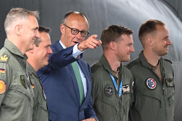 German Chancellor Friedrich Merz gestures standing among German air force personell at the opening day of International Aerospace Exhibition (ILA) in Schoenefeld, near Berlin on June 10, 2026. (Photo by RALF HIRSCHBERGER / AFP)