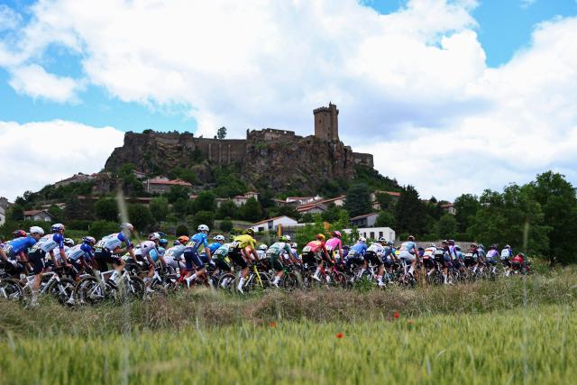 The pack of riders (peloton) cycles past the Chateau de Polignac during the 4th stage of the Tour Auvergne-Rhone-Alpes cycling race (formerly known as the Criterium du Dauphine), 167,4km between Le Puy-en-Velay and Montrond-les-Bains, central France, on June 10, 2026. (Photo by Anne-Christine POUJOULAT / AFP)