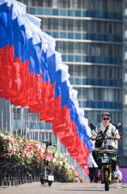 A cyclist rides past Russian national flags decorating a bridge in downtown Moscow on June 10, 2026 prior to the Russia Day celebration to be marked on June 12. (Photo by Alexander NEMENOV / AFP)