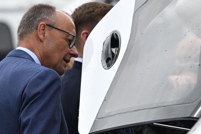 German Chancellor Friedrich Merz looks at an Airbus helicopter during a visit at the International Aerospace Exhibition (ILA) in Schoenefeld, near Berlin on June 10, 2026. Born on May 9, 2026 'Broetchen' is the last addition to the pygmy hippopotamus family at the Zoo in the German capital. (Photo by RALF HIRSCHBERGER / AFP)