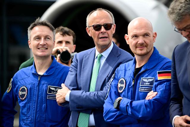 German Chancellor Friedrich Merz looks on with sunglasses near Alexander Gerst (R) and Matthias Maurer (L), astronauts of the European Space Agency (ESA) during the opening day of International Aerospace Exhibition (ILA) in Schoenefeld, near Berlin on June 10, 2026. (Photo by Tobias SCHWARZ / AFP)