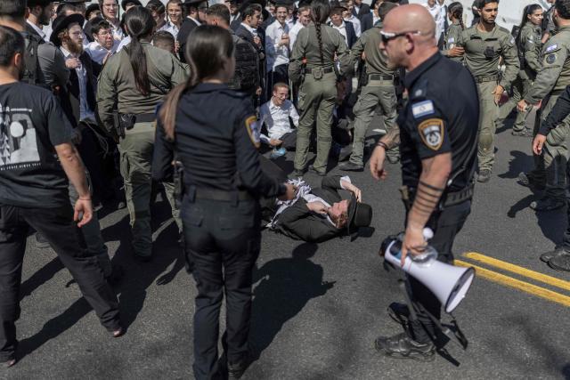 Israeli security forces attempt to disperse ultra-Orthodox Jews trying to block the entrance to the Abu Kabir holding facility in Tel Aviv in protest against the recent arrests of ultra-Orthodox draft dodgers on June 10, 2026. Israel's High Court of Justice in April ordered the state to cut financial benefits to ultra-Orthodox Jews who dodge being drafted and to start criminal proceedings against them. There is a long-standing exemption from compulsory national service for ultra-Orthodox men who engage in full-time religious study, which dates back to Israel's founding in 1948. However, the Supreme Court has repeatedly challenged the exemption in recent years, culminating in a 2024 ruling that the government must conscript ultra-Orthodox men. (Photo by ilia YEFIMOVICH / AFP)