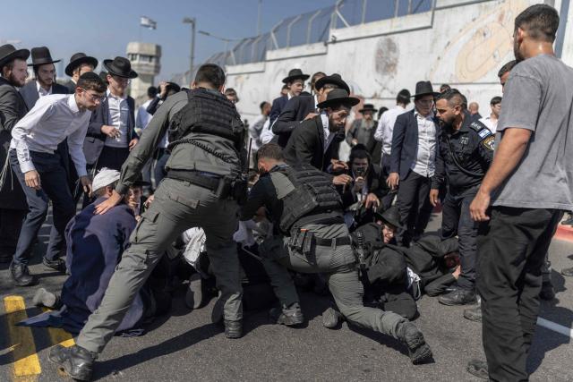 Israeli security forces attempt to disperse ultra-Orthodox Jews trying to block the entrance to the Abu Kabir holding facility in Tel Aviv in protest against the recent arrests of ultra-Orthodox draft dodgers on June 10, 2026. Israel's High Court of Justice in April ordered the state to cut financial benefits to ultra-Orthodox Jews who dodge being drafted and to start criminal proceedings against them. There is a long-standing exemption from compulsory national service for ultra-Orthodox men who engage in full-time religious study, which dates back to Israel's founding in 1948. However, the Supreme Court has repeatedly challenged the exemption in recent years, culminating in a 2024 ruling that the government must conscript ultra-Orthodox men. (Photo by ilia YEFIMOVICH / AFP)