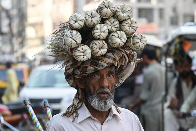 A vendor selling brooms looks for customers at a market in Rawalpindi on June 10, 2026. (Photo by Farooq NAEEM / AFP)