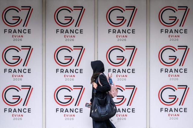 A passer-by walks past logos of the G7 summit in Evian, central-eastern France on June 10, 2026. (Photo by Fabrice COFFRINI / AFP)