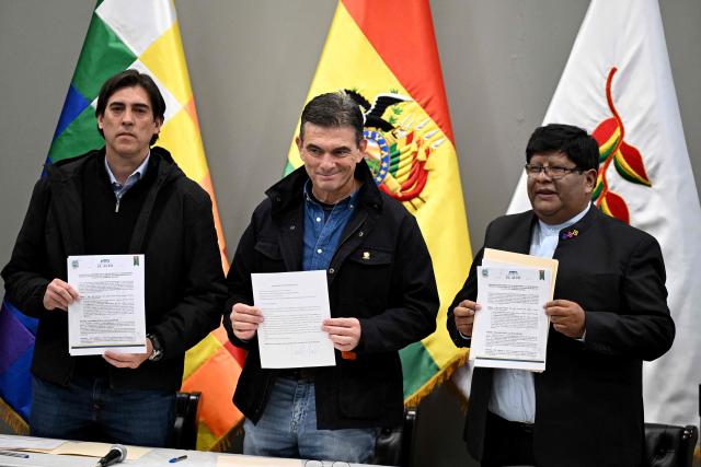 Bolivia's President Rodrigo Paz (C), Public Works Minister Mauricio Zamora Liebers (L) and El Alto Mayor Eliser Roca hold signed copies of an agreement at the Casa Grande del Pueblo, seat of the presidential palace, in La Paz on June 10, 2026. For weeks, protesters demanding that US-backed conservative President Rodrigo Paz's fledgling government address a deep economic crisis, while others called for his resignation, have marched and set up roadblocks, bringing Bolivia to a near standstill, driving up food and fuel prices and causing shortages of basic goods. (Photo by MARVIN RECINOS / AFP)