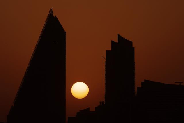 The sun sets behind the Doha skyline on June 10, 2026. (Photo by Karim JAAFAR / AFP)