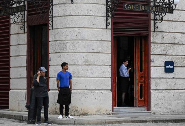 Employees at a state-run cafe check their mobile phones during a power outage in Havana on June 10, 2026. (Photo by YAMIL LAGE / AFP)