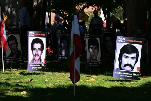 Placards of former Iranian athletes lie in the grass during a press conference held by the National Council of Resistance of Iran, who is calling on FIFA to suspend and expel the Iranian regime-controlled "Football Federation Islamic Republic of Iran" from international football, at Los Angeles City Hall, in Los Angeles, on June 10, 2026. (Photo by Frederic J. Brown / AFP)