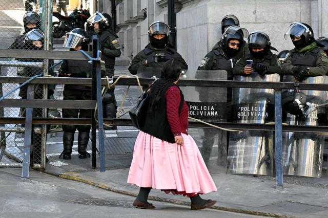 A woman walks past a riot police barricade during a protest against the government of Bolivia's President Rodrigo Paz in La Paz on June 10, 2026. For weeks, protesters demanding that US-backed conservative President Rodrigo Paz's fledgling government address a deep economic crisis, while others called for his resignation, have marched and set up roadblocks, bringing Bolivia to a near standstill, driving up food and fuel prices and causing shortages of basic goods. (Photo by AIZAR RALDES / AFP)