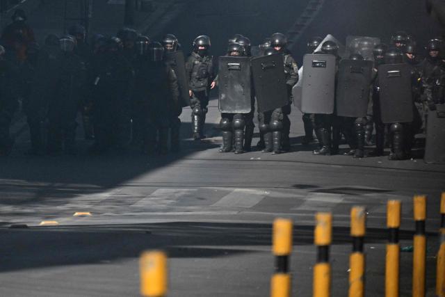 Riot police officers take cover behind shields during a protest against the government of Bolivia's President Rodrigo Paz in La Paz on June 10, 2026. For weeks, protesters demanding that US-backed conservative President Rodrigo Paz's fledgling government address a deep economic crisis, while others called for his resignation, have marched and set up roadblocks, bringing Bolivia to a near standstill, driving up food and fuel prices and causing shortages of basic goods. (Photo by MARVIN RECINOS / AFP)