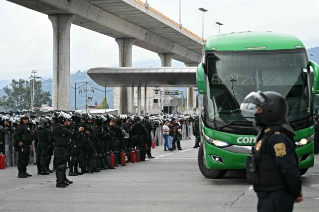 Police stand guard during an operation that keeps retained buses transporting students from Ayotzinapa who try to enter the city and join the protests of teachers and relatives of missing people ahead of the start of the 2026 FIFA World Cup, on the outskirts of Mexico City, on June 10, 2026. (Photo by YURI CORTEZ / AFP)
