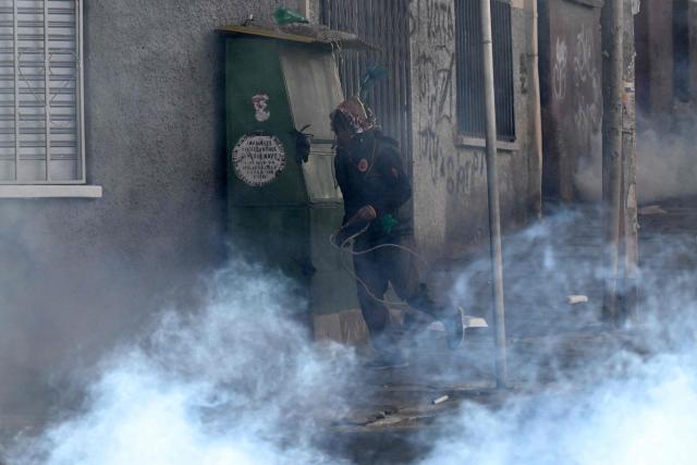 A man runs from tear gas during a protest against the government of Bolivia's President Rodrigo Paz in La Paz on June 10, 2026. For weeks, protesters demanding that US-backed conservative President Rodrigo Paz's fledgling government address a deep economic crisis, while others called for his resignation, have marched and set up roadblocks, bringing Bolivia to a near standstill, driving up food and fuel prices and causing shortages of basic goods. (Photo by MARVIN RECINOS / AFP)