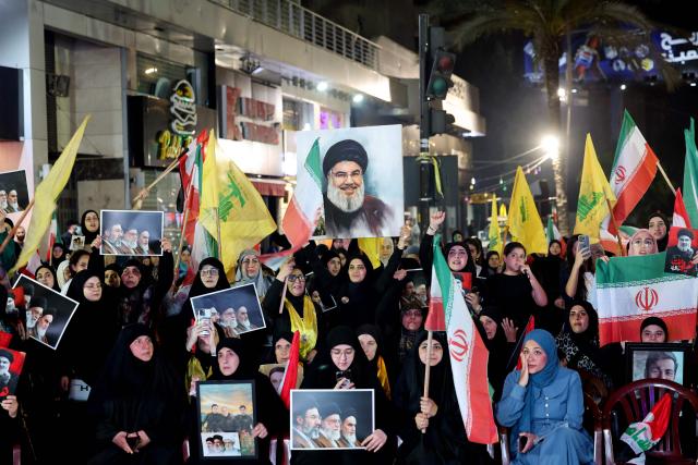 Supporters of Iran-backed armed group Hezbollah, wave flags and hold a portrait of slain leader Hassan Nasrallah during an anti-US and anti-Israel protest organised by the International Popular Committees to Resist Aggression in Beirut’s southern suburbs on June 10, 2026. Israeli airstrikes on Lebanon killed at least 12 people on June 10, a medical source told AFP, as Israeli Prime Minister Benjamin Netanyahu urged the Lebanese people to join Israel's fight against Hezbollah. (Photo by Anwar AMRO / AFP) / 