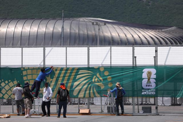 Workers set up a banner on a fence around the Monterrey stadium, which will host four matches of the 2026 World Cup football tournament, in Guadalupe, Nuevo Leon, Mexico, on June 10, 2026. (Photo by Julio Cesar AGUILAR / AFP)