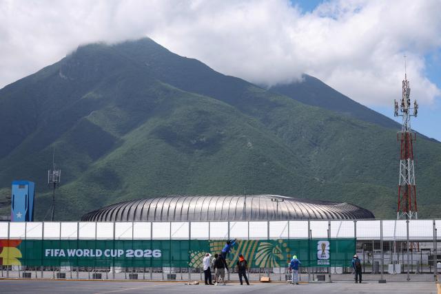 Workers set up a banner on a fence around the Monterrey stadium, which will host four matches of the 2026 World Cup football tournament, in Guadalupe, Nuevo Leon, Mexico, on June 10, 2026. (Photo by Julio Cesar AGUILAR / AFP)