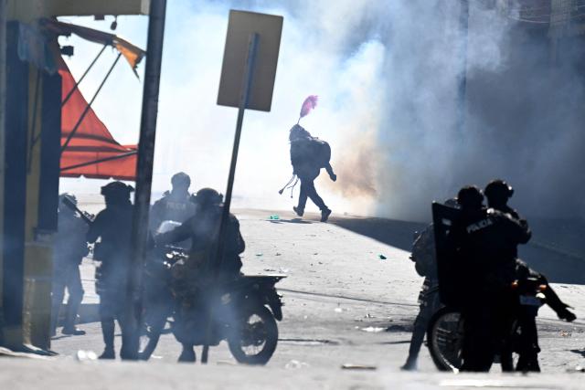 A demonstrator walks past police officers on motorcycles amid tear gas smoke during a protest against the government of Bolivia's President Rodrigo Paz in La Paz on June 10, 2026. For weeks, protesters demanding that US-backed conservative President Rodrigo Paz's fledgling government address a deep economic crisis, while others called for his resignation, have marched and set up roadblocks, bringing Bolivia to a near standstill, driving up food and fuel prices and causing shortages of basic goods. (Photo by MARVIN RECINOS / AFP)