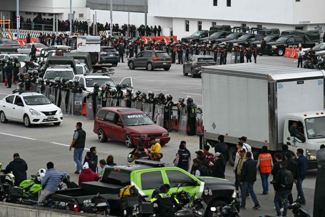 Police stand guard during an operation that keeps retained buses transporting students from Ayotzinapa who try to enter the city and join the protests of teachers and relatives of missing people ahead of the start of the 2026 FIFA World Cup, on the outskirts of Mexico City, on June 10, 2026. (Photo by YURI CORTEZ / AFP)