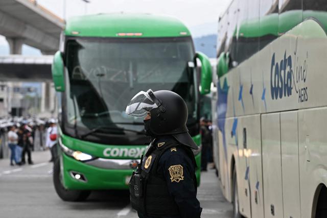 A police officer stands guard during an operation that keeps retained buses transporting students from Ayotzinapa who try to enter the city and join the protests of teachers and relatives of missing people ahead of the start of the 2026 FIFA World Cup, on the outskirts of Mexico City, on June 10, 2026. (Photo by YURI CORTEZ / AFP)
