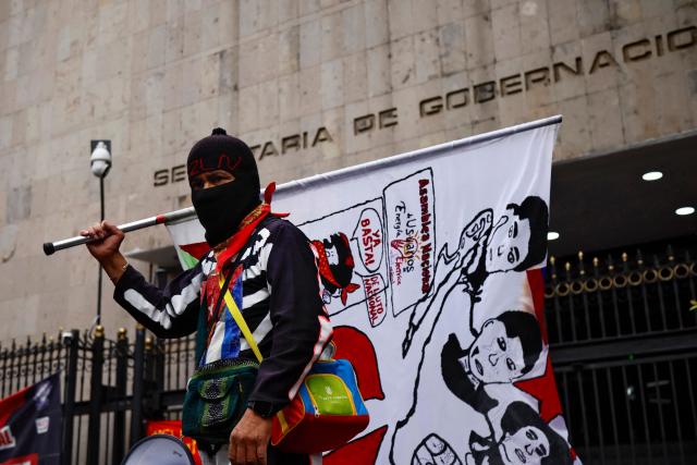 A protester with a flag of the Zapatista Army of National Liberation (EZLN) takes part in a demonstration by the National Coordinator of Education Workers (CNTE) ahead of the start of the 2026 FIFA World Cup outside of the Interior Ministry building in Mexico City, on June 10, 2026. (Photo by Rodrigo Oropeza / AFP)