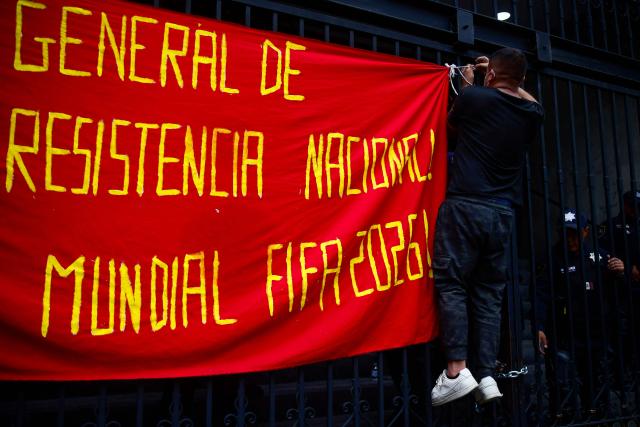 A protester hangs a banner during a demonstration by the National Coordinator of Education Workers (CNTE) ahead of the start of the 2026 FIFA World Cup outside of the Interior Ministry building in Mexico City, on June 10, 2026. (Photo by Rodrigo Oropeza / AFP)